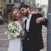 Elegant couple embracing on urban street, holding bouquet, perfect for wedding or romantic themes.