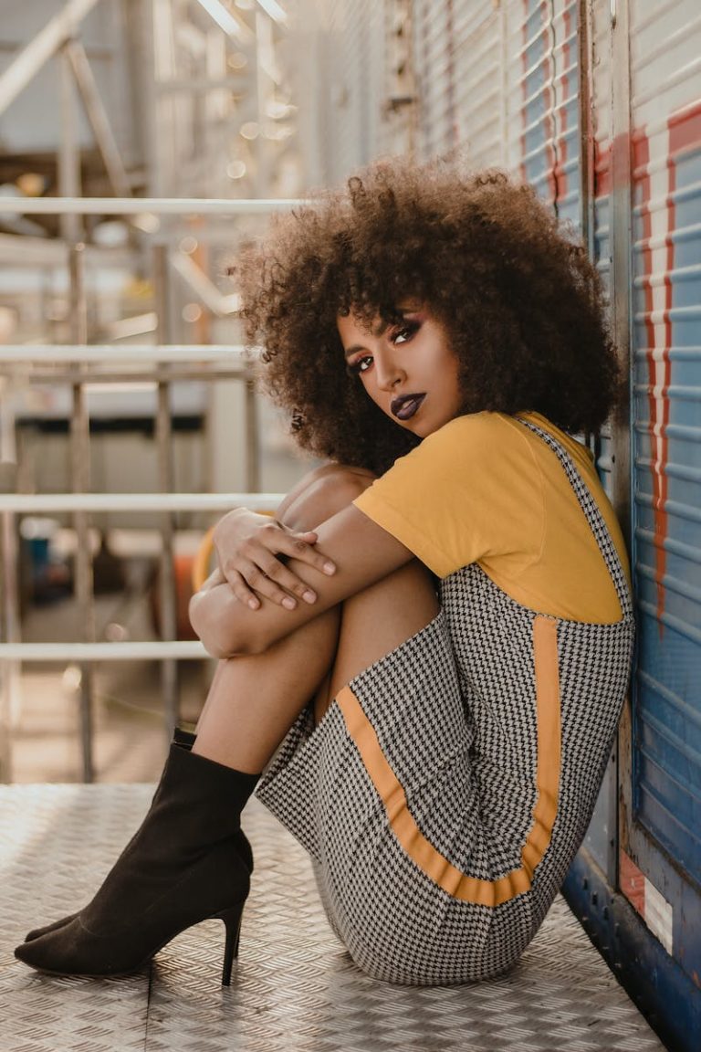 Fashionable portrait of a woman posing with a stylish afro hairstyle outdoors.
