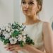 A bride holding a cotton and eucalyptus bouquet, showcasing elegance and style indoors.