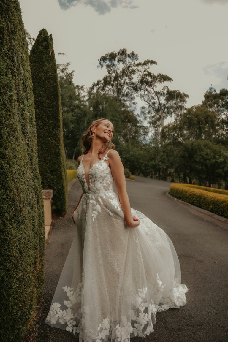 a woman in a wedding dress standing in front of a hedge